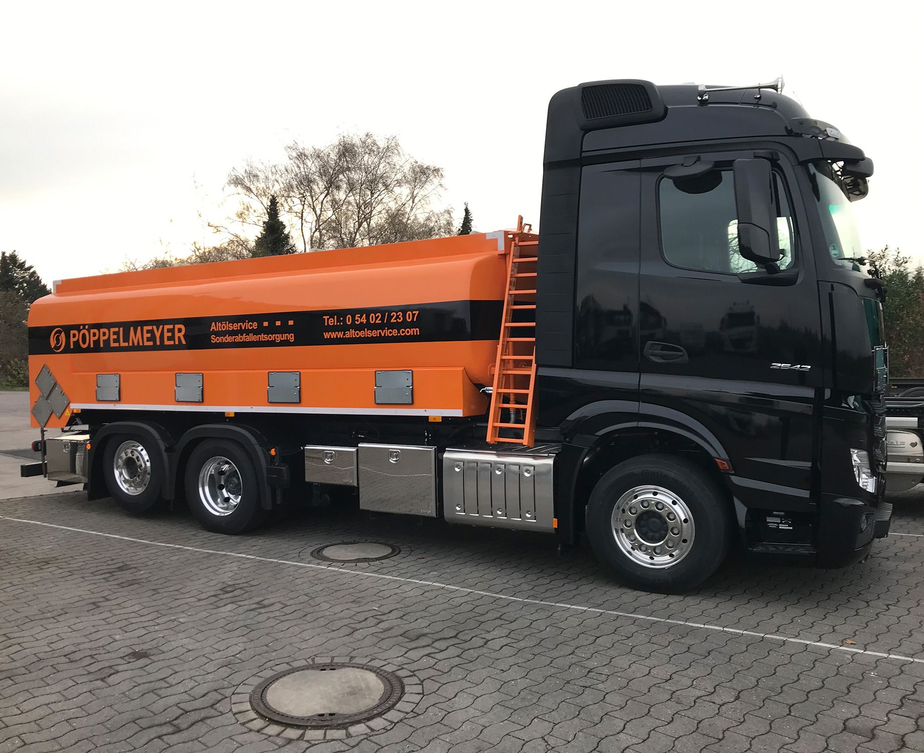 Schwarzer LKW mit orangenem Anhänger
